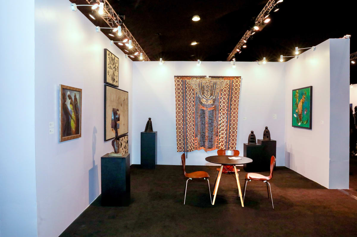 A contemporary art booth at ART X Lagos 2025, with paintings and sculpture arranged around a textile work