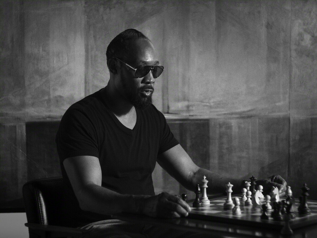 A man in sunglasses studies a chessboard in an official Netflix still for The Disciple