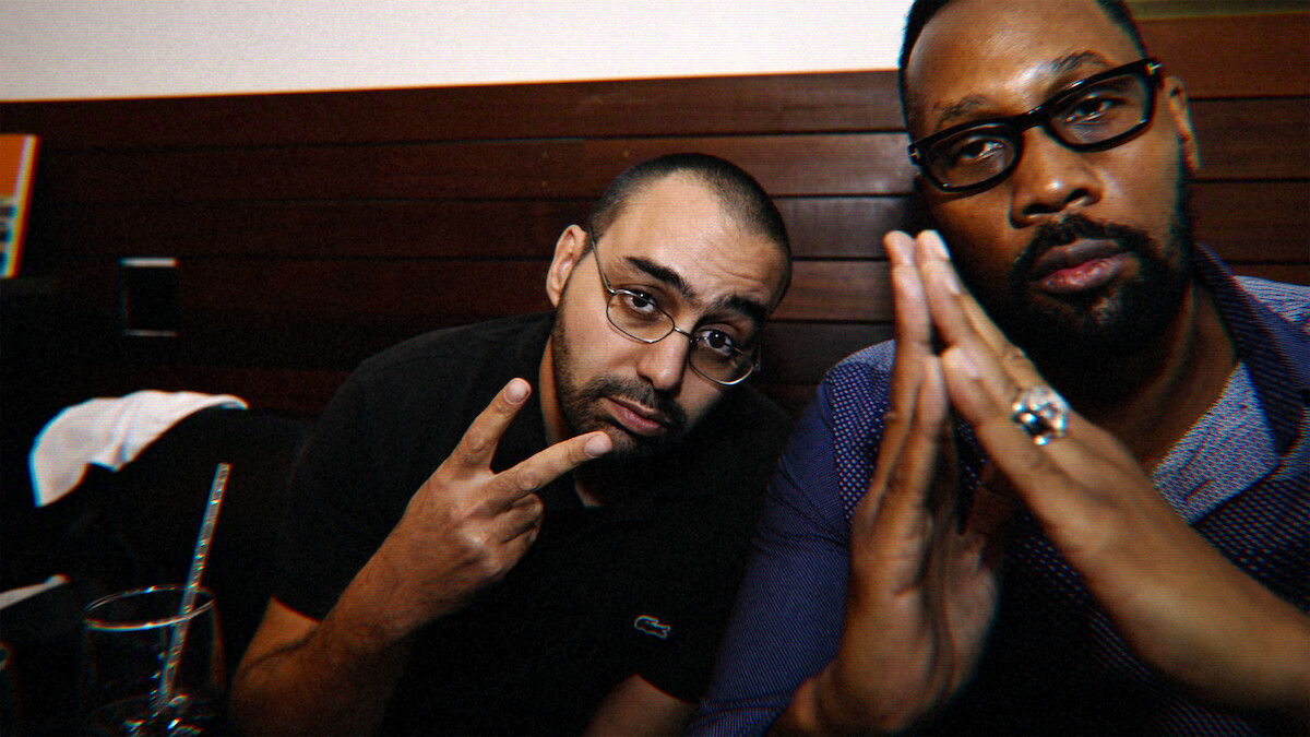 the-disciple-netflix-wu-tang-cilvaringz-october-2026-cover Two men in glasses sit together in a dimly lit room in an official still from The Disciple: A Wu-Tang Fable