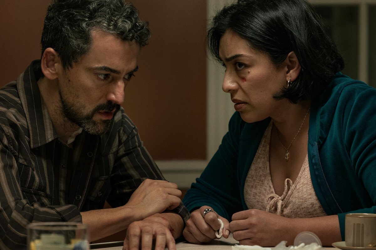 Two concerned adults sit at a table during a tense conversation in Netflix’s Animals