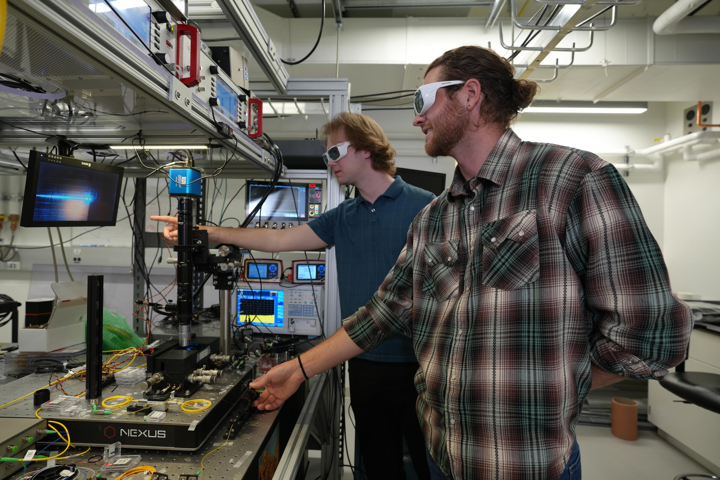 NIST researchers aligning an optical fibre with an integrated photonics chip in a laboratory