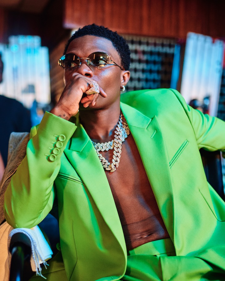 Wizkid performing on stage in a green jacket
