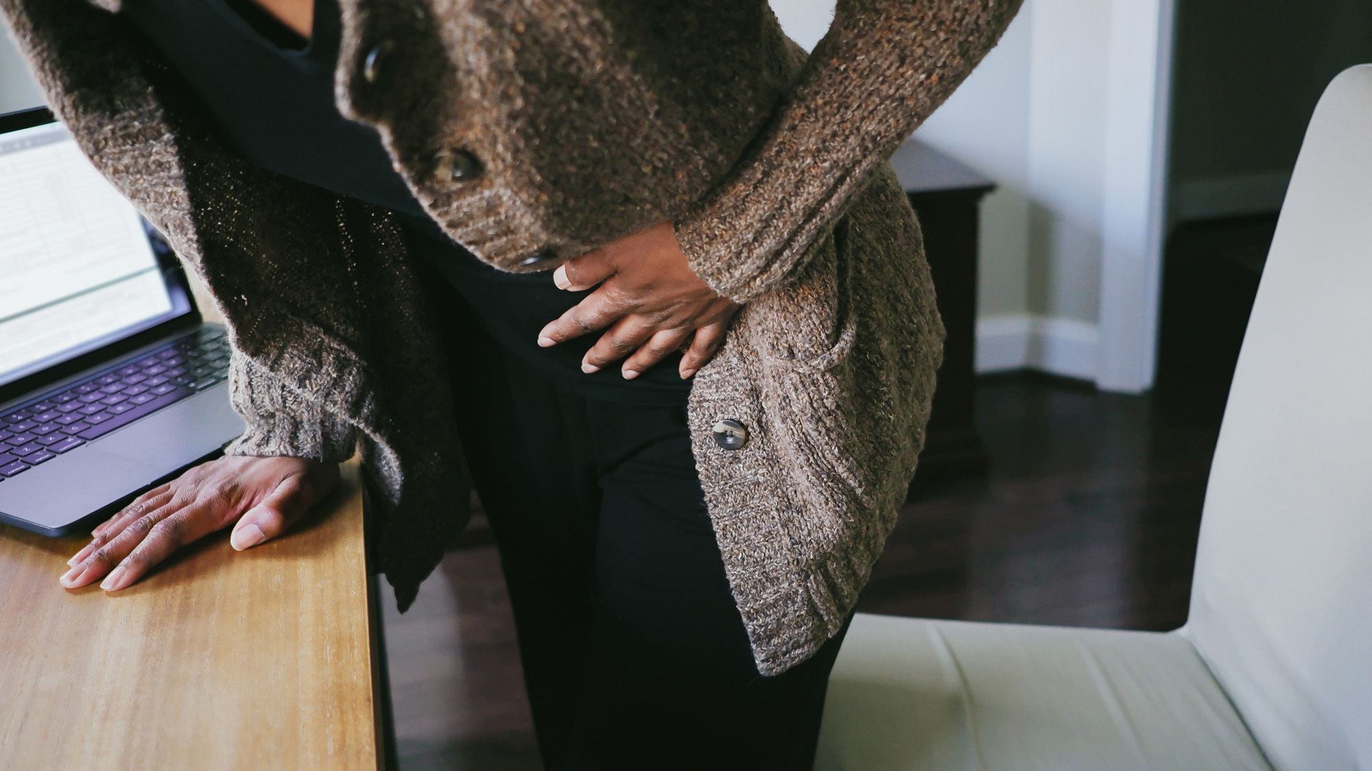 Illustrative photograph of a woman holding her abdomen to represent endometriosis pain